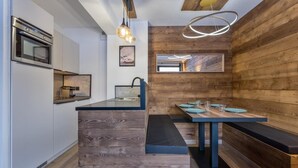 Eine moderne Küche mit eingebauten Geräten, einer Wand mit Holzvertäfelung und einem Essbereich mit einer Bank und Tisch.