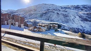 Un paisaje montañoso cubierto de nieve, con edificios y un cielo despejado.