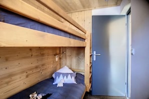 Ein Etagenbett mit Holz-Kopfteil, einem kleinen Nachttisch und einem Kissen.