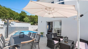 An outdoor patio with a pool, dining table, chairs, and an umbrella. - Villa Marko by Aneo Travel (Ledenice)