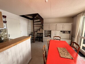 A compact kitchen with a wooden countertop, a dining table with a red tablecloth, and a staircase leading to an upper level.