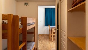A dormitory room with bunk beds, a desk, and a chair.