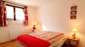 A bedroom with a bed, two bedside tables, a radiator, and a wall-mounted picture frame.