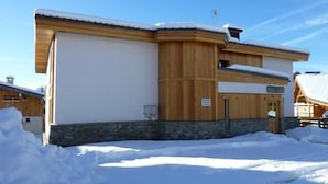 A wooden building with a stone foundation, a sign indicating a restaurant, and snow-covered surroundings.