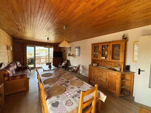 A cozy living room with a sofa, a dining table with placemats, and a wooden cabinet.