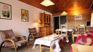 A cozy room with a bed, two chairs, a wooden cabinet, and a table. - 50m from ski slopes, 2nd floor, balcony, tv, 66m², Alpe d'Huez (L'Alpe d'Huez)