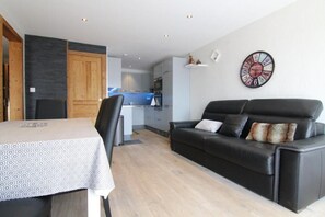 Cozy living area with a dining table for two, a comfortable sofa, and a fully equipped kitchen.