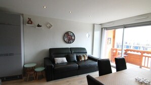 En moderne stue med en sort lædersofa, et spisebord og et lille rundt bord.