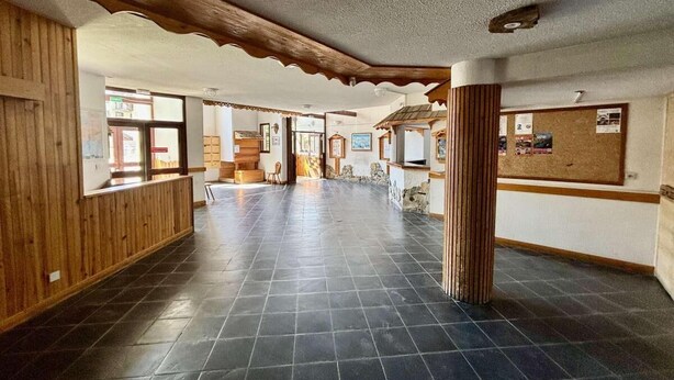 A spacious lobby with a tiled floor, wooden paneling on the walls, and a reception desk.
