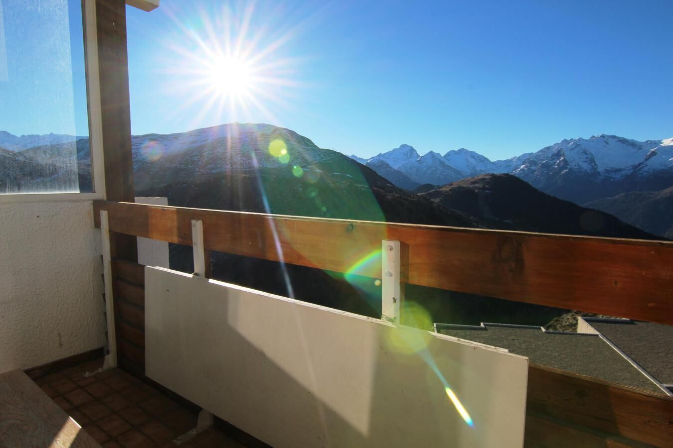 A balcony with a view of snow-capped mountains and a clear sky.