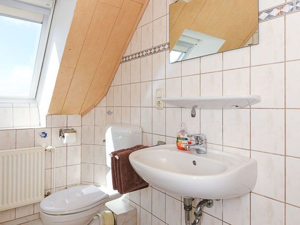 Une salle de bain équipée d’un WC, d’un lavabo, d’un miroir et d’un porte-serviettes.
