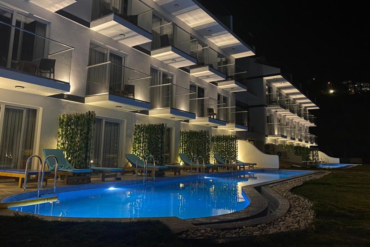 Un hôtel moderne doté de nombreux balcons, d’une piscine et d’un espace extérieur aménagé pour se détendre.