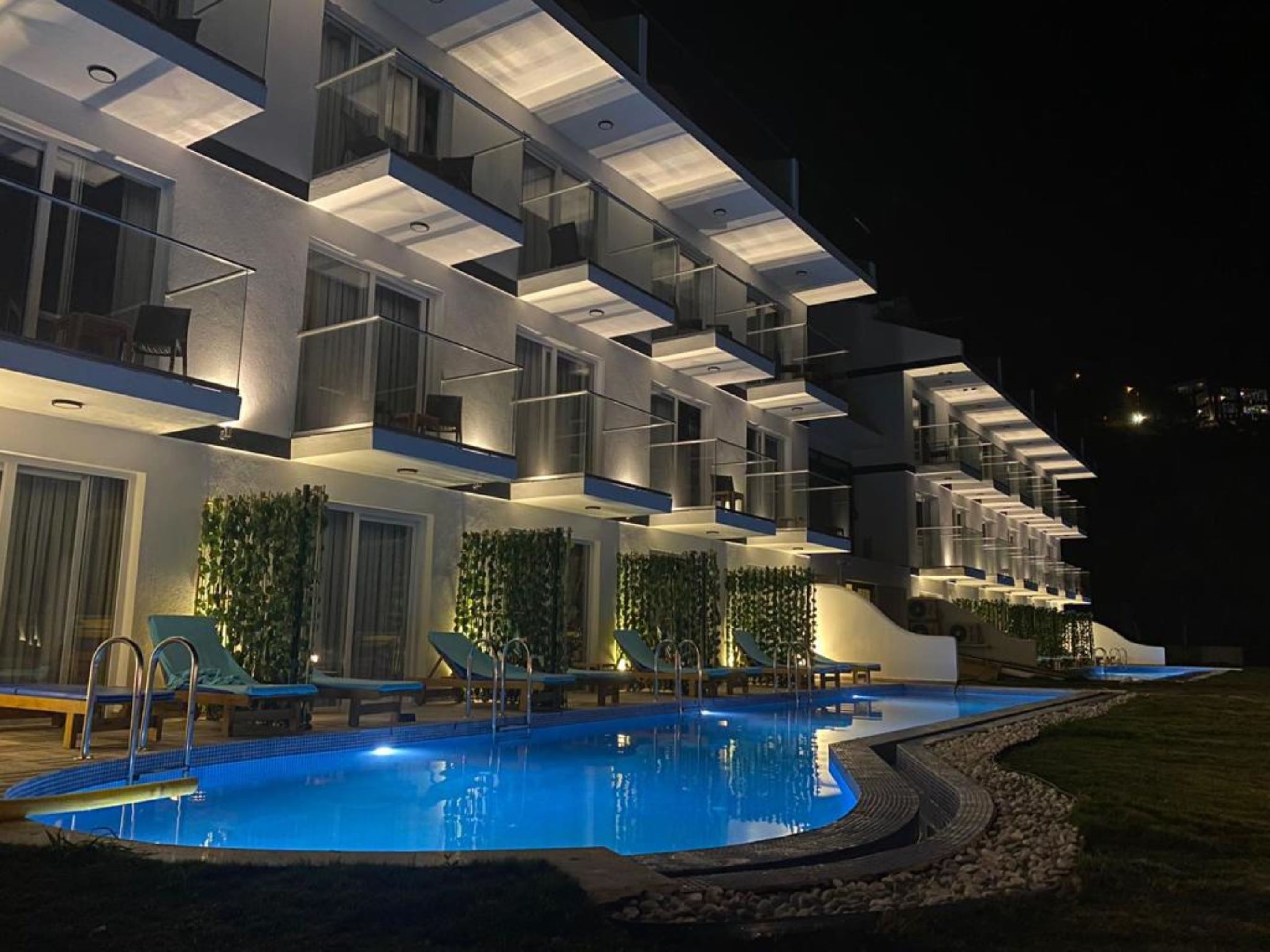 A modern hotel with a pool area, featuring multiple balconies and a well-lit exterior.