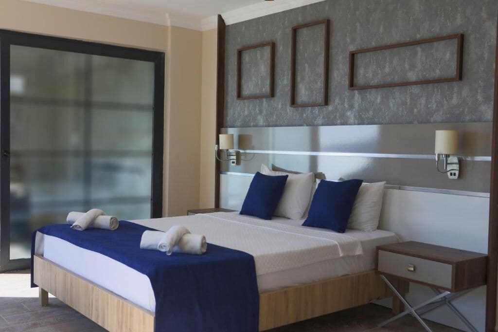 A modern hotel room with a large bed, a bedside table, and a nightstand.