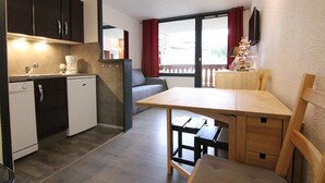 A compact kitchen with a dishwasher, a small refrigerator, and a dining area with a table and chairs. - 100m from ski slopes, 3rd floor, balcony, tv, ski locker, 24m², Alpe d'Huez (L'Alpe d'Huez)