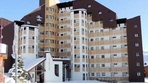 A multi-story hotel with a modern design, featuring balconies and a central entrance. - 100m from ski slopes, 3rd floor, balcony, tv, ski locker, 24m², Alpe d'Huez (L'Alpe d'Huez)