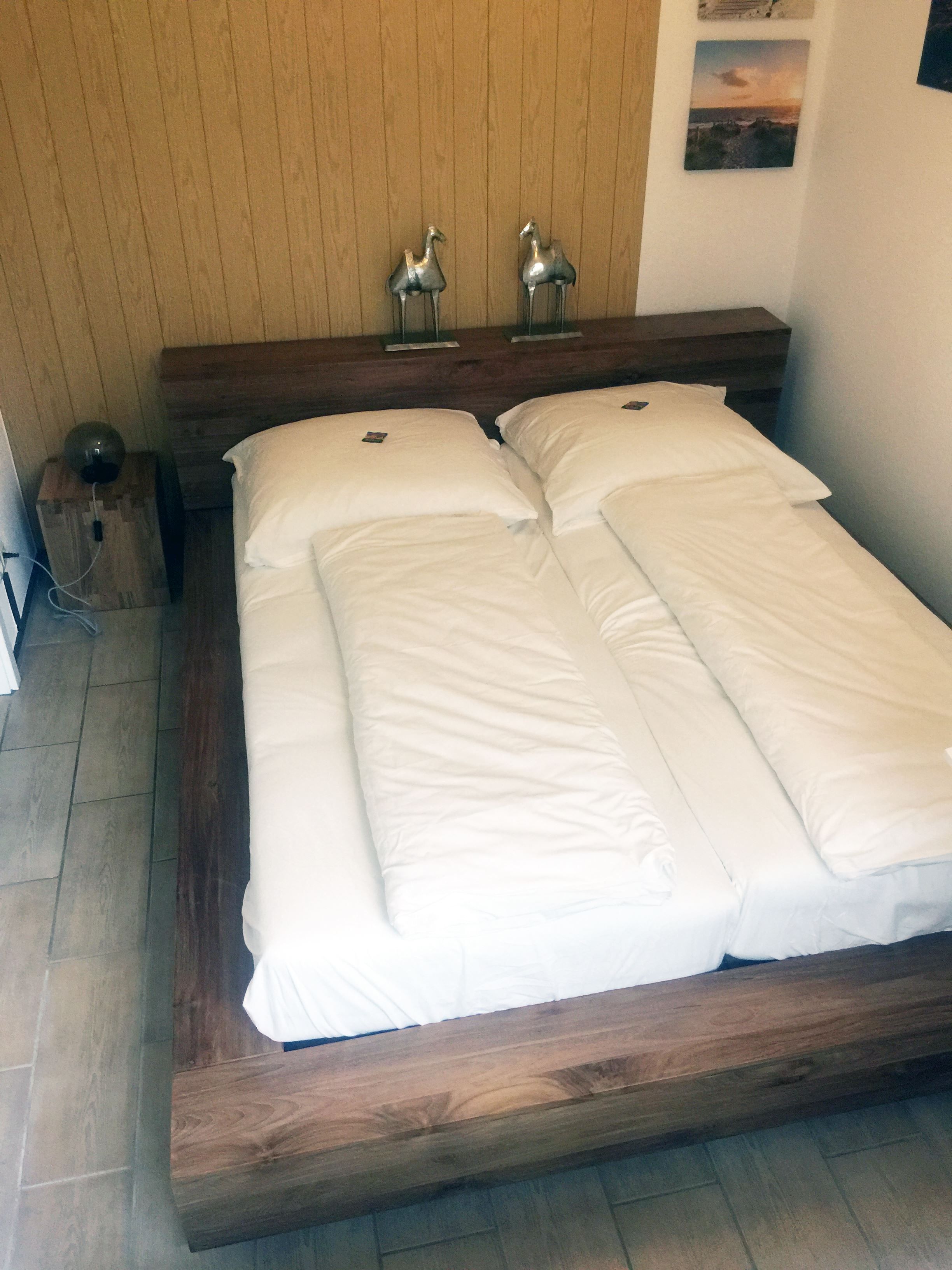 Un letto matrimoniale con biancheria da letto bianca in una stanza con pareti di legno e una testiera in legno.