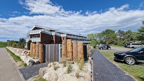 A modern building with a wooden facade, a balcony, and a paved walkway.