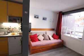 Habitació senzilla amb llit, petita cuina i balcó.