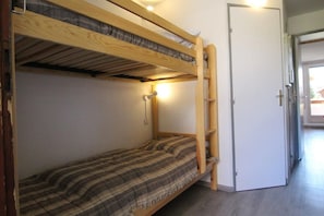 Un llit superposat amb estructura de fusta, un llit individual a la part inferior i una porta a la dreta.
