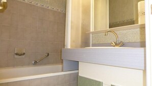 Een badkamer met een bad, een wastafel en een spiegel.