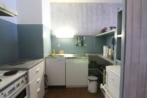 A compact kitchen with a dishwasher, stove, and a small sink.