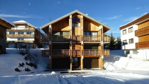 Un immeuble en bois à plusieurs étages, doté de balcons, et entouré de neige.