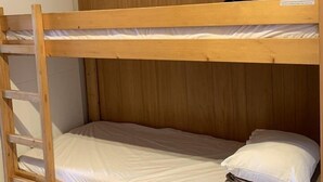 Un lit superposé avec une tête de lit en bois et une échelle.