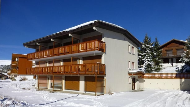 Un edificio de varios pisos con balcones y un paisaje cubierto de nieve.