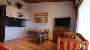 Un espacio habitable compacto con kitchenette, comedor, televisor y cama.