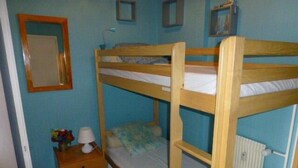 Habitación con literas, un aparador de madera, un espejo y un radiador.