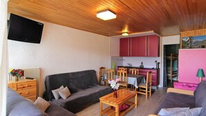 Una sala de estar acogedora con un sofá, una mesa de centro de madera y un televisor montado en la pared.
