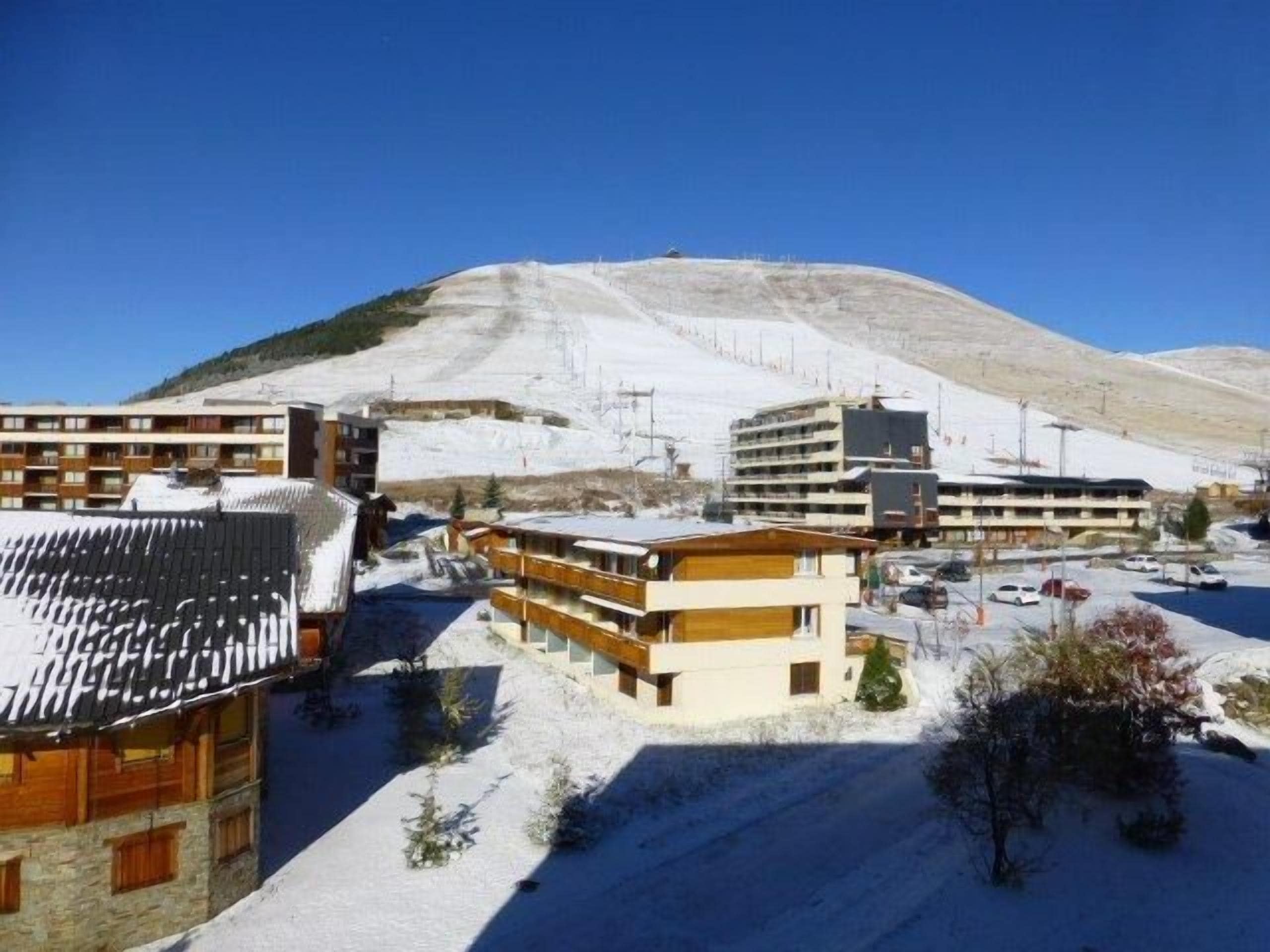 A snow-covered building complex with multiple floors and a mountain in the background.