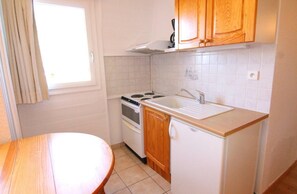 A compact kitchen with a stove, sink, and wooden cabinets. - 220m from ski slopes, 3rd floor, tv, ski locker, 22m², Alpe d'Huez (L'Alpe d'Huez)