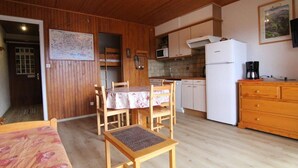 Une cuisine compacte dotée de meubles en bois, d’un four à micro-ondes, d’un réfrigérateur et d’un coin repas avec une table et des chaises.