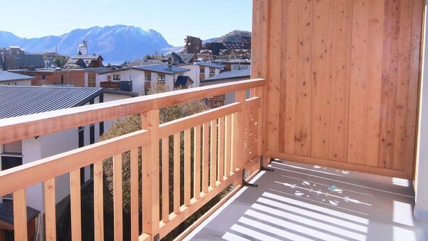 Un balcon en bois offrant une vue sur un paysage montagneux.