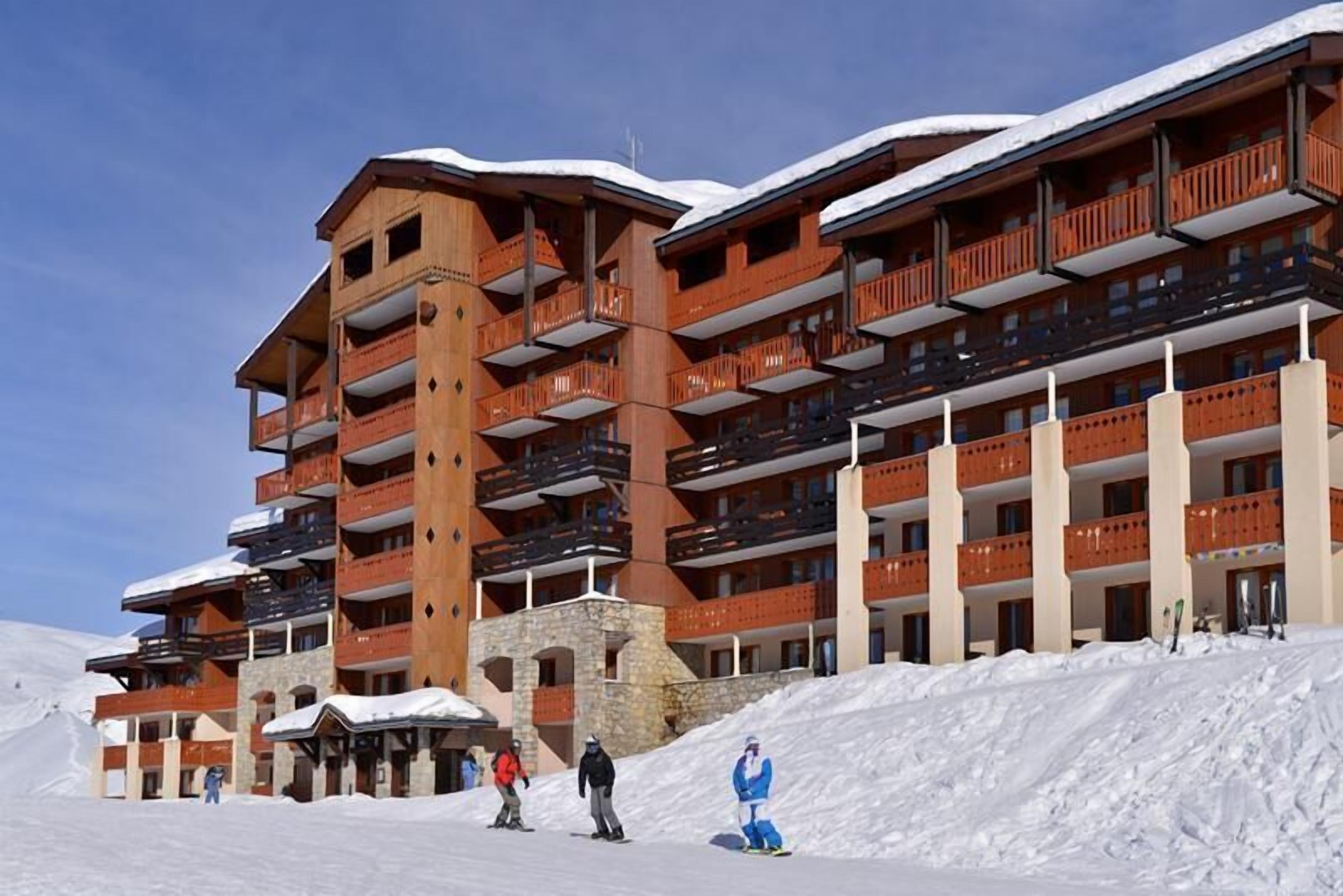 A multi-story hotel with balconies, ski slopes, and snow-covered surroundings.