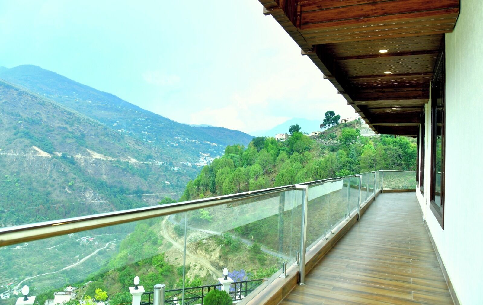 A balcony with a glass railing overlooking a mountainous landscape.