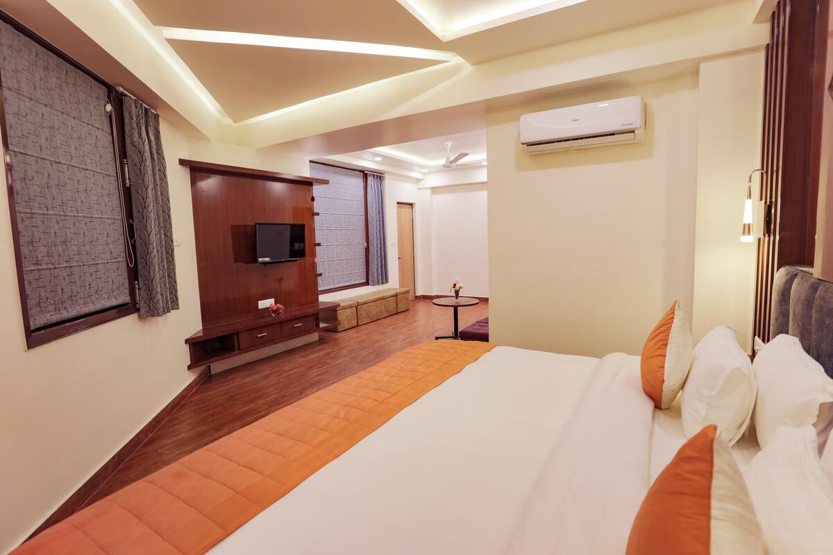 Ein modernes Hotelzimmer mit einem großen Bett, einem Fernseher, einem kleinen Tisch und einer Couch.