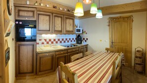 Una cocina con armarios de madera, microondas, cafetera y una mesa con sillas.