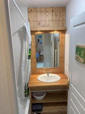 A bathroom with a wooden vanity, a sink, a mirror, and a shower curtain. - Ski-in/ski-out & foot of the slopes, 5th floor, swimming pool, sauna, balcony, tv, ski locker, 33m² (Les Orres)