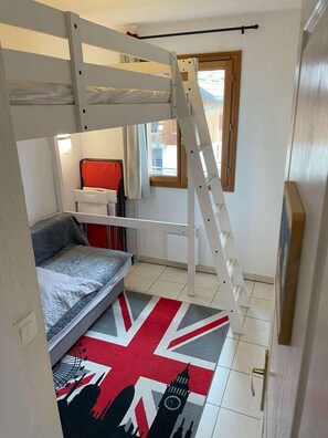 Una habitación pequeña con una cama individual doble, un escritorio y una silla.