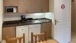 Una cocina compacta con armarios de madera, microondas, cafetera y lavavajillas.