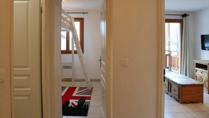 Un pasillo con una escalera, una puerta, un ventanal y un televisor en una habitación.