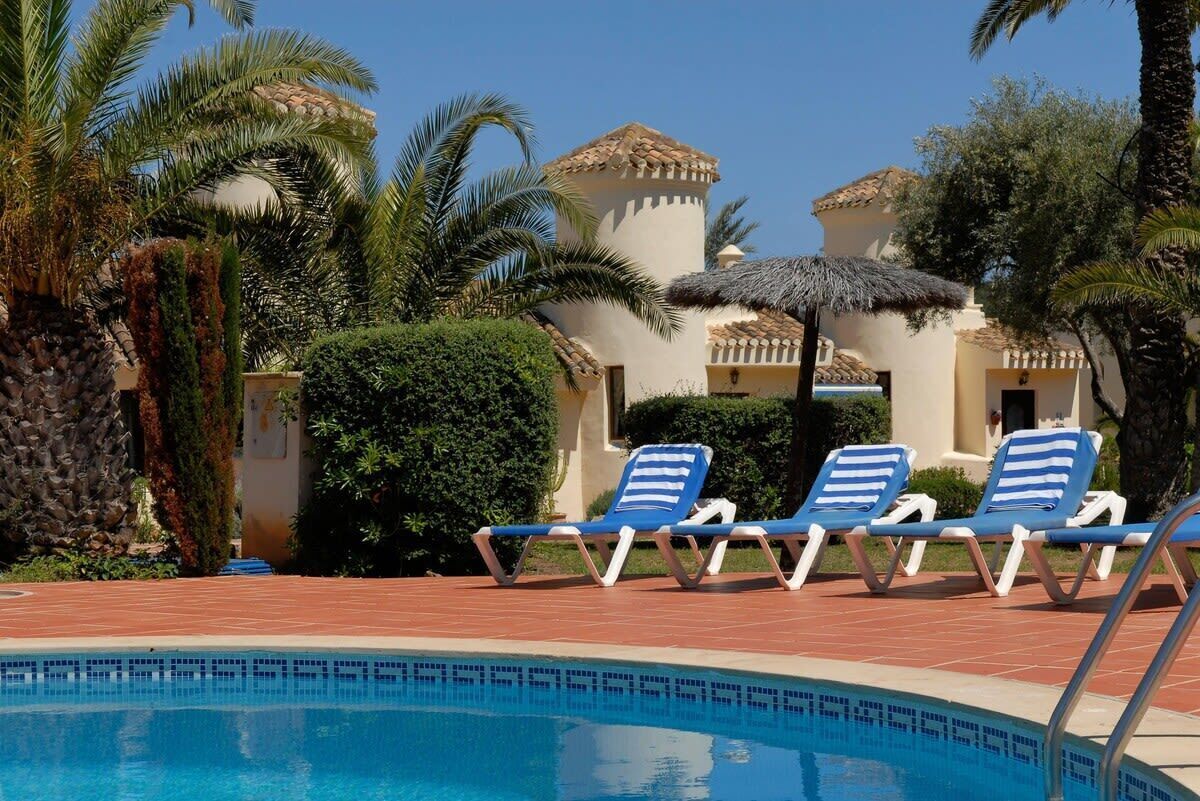 A pool area with lounge chairs and palm trees.