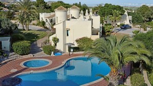 A resort with a large pool, palm trees, and a Mediterranean-style building. - La Manga Club El Rancho Townhouse 399 (La Manga Club, Cartagena)