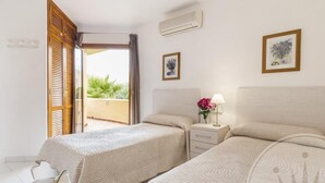 A hotel room with two beds, a small bedside table with a lamp, and a view of the outdoors. - La Manga Club El Rancho Townhouse 399 (La Manga Club, Cartagena)