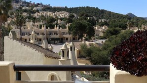 A coastal town with terraced houses, a church, and a hill in the background. - La Manga Club El Rancho Townhouse 399 (La Manga Club, Cartagena)