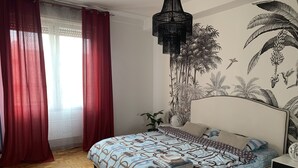 A bedroom with a bed, red curtains, a wall mural, a hanging light fixture, and a small plant. - Center Salo’, near to Duomo,  to Vittoriale D’Annunzio (Salò)