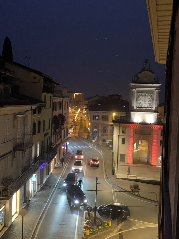A nighttime street view with buildings, a clock tower, and a red-lit archway.